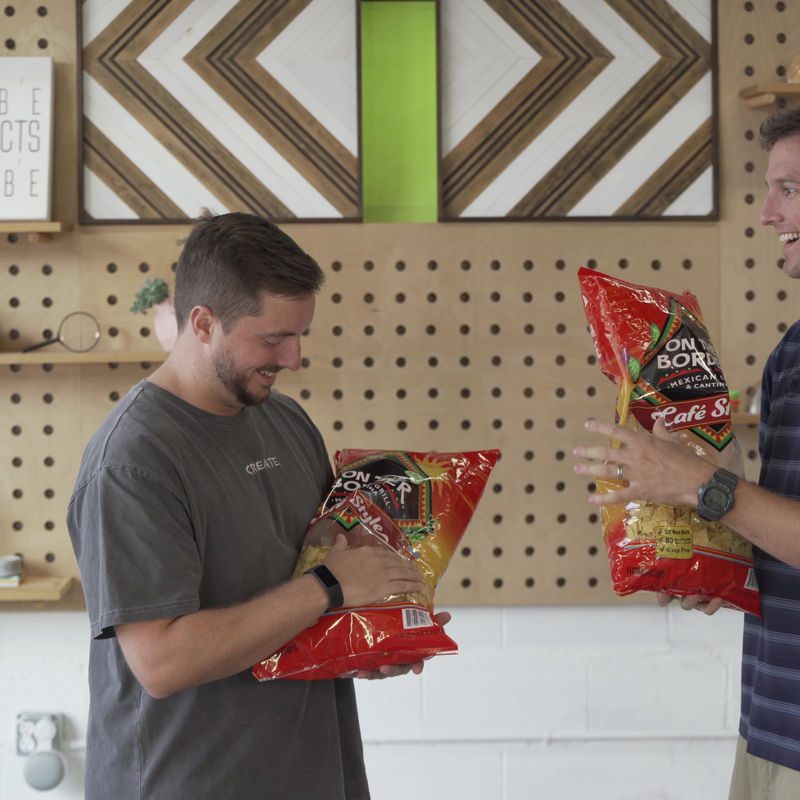 Johnny Saye and John Hawley laughing with bags of chips